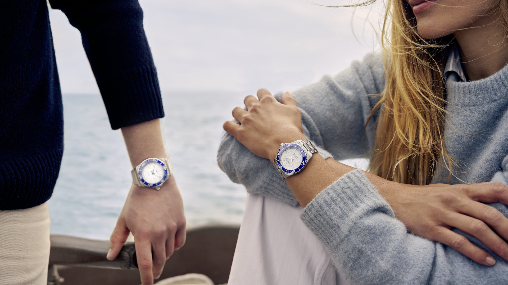 Ein Paar trägt die neuen Uhren von Longines HydroConquest Sylt Edition auf einem Boot vor Meer und Wasser